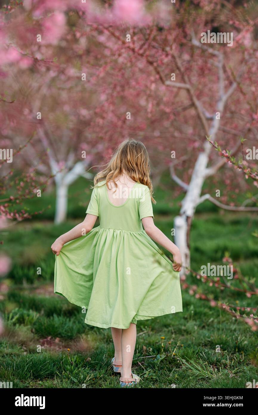 Ragazza che tiene in mano un vestito in un frutteto in fiore rosa Foto Stock