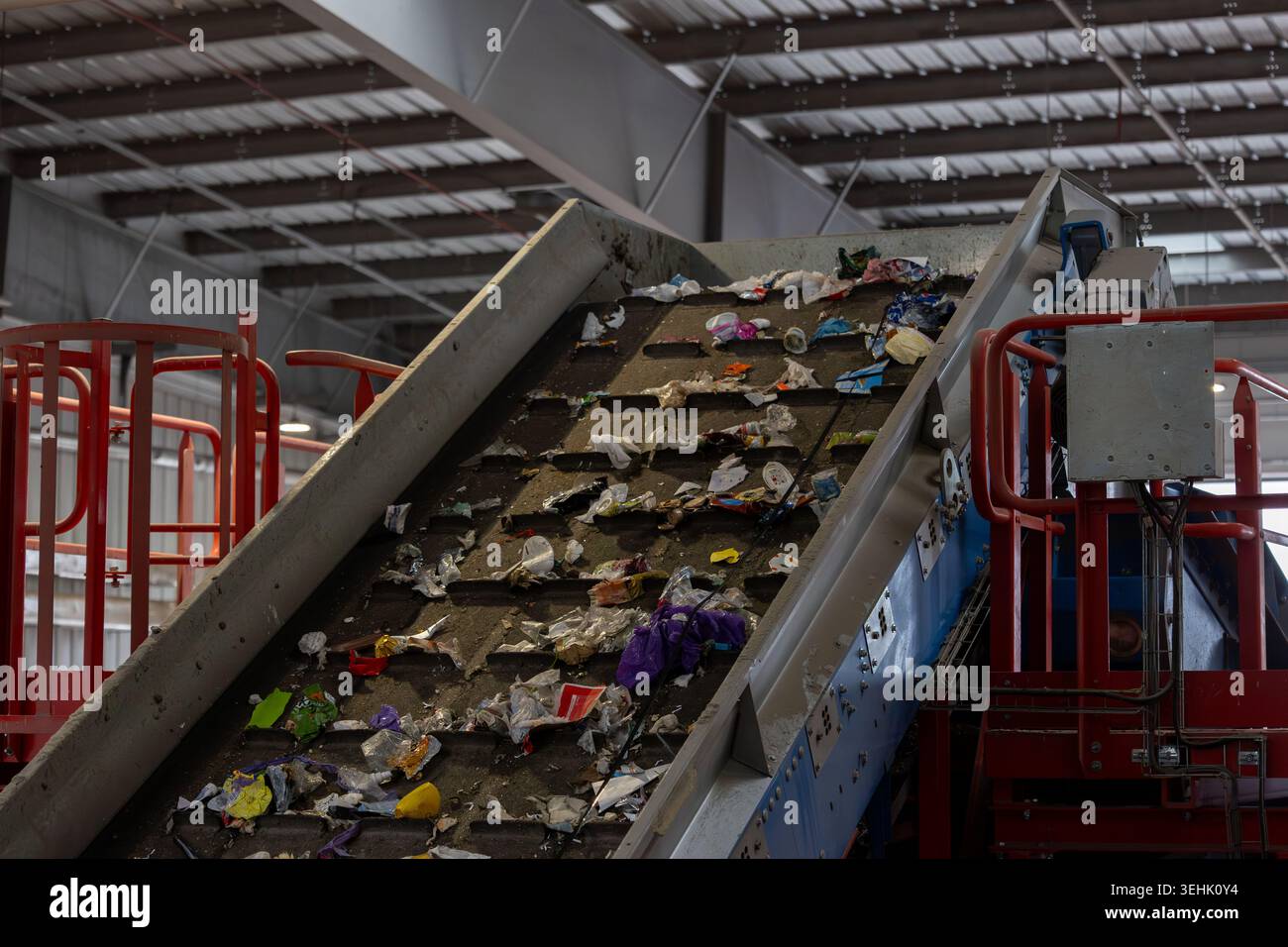 Impianto di smistamento dei rifiuti che mostra il nastro trasportatore inclinato che trasporta rifiuti urbani misti. Imballaggi, pellicole e contenitori in plastica Foto Stock