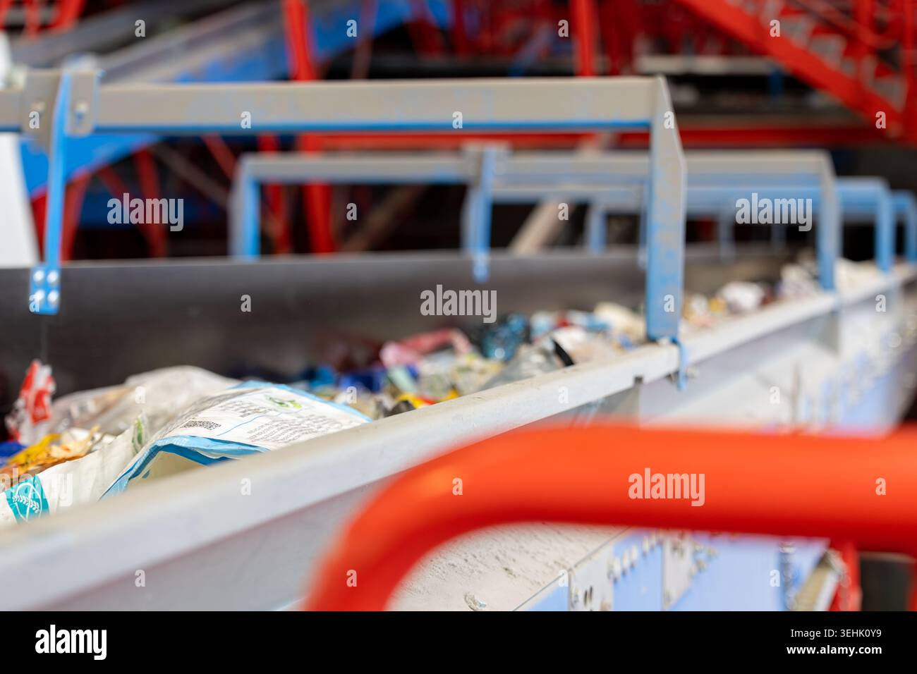 Nastro trasportatore che trasporta materiali di scarto misti all'interno di un impianto di riciclaggio. Sistema di smistamento automatizzato con strutture metalliche e piattaforme industriali Foto Stock