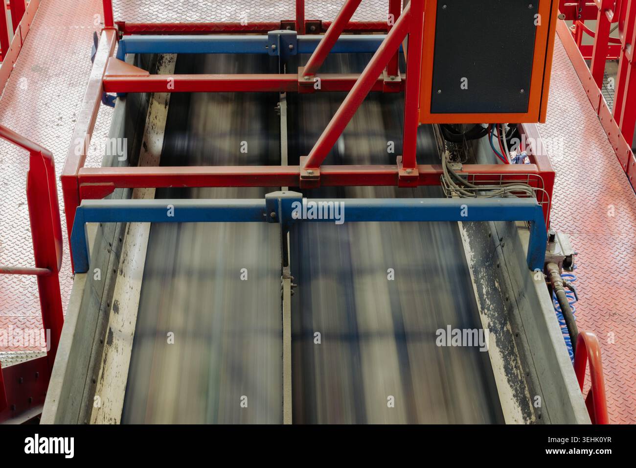 Nastro trasportatore ad alta velocità che opera all'interno di un impianto di riciclaggio. Sistema di trasporto industriale con macchinari automatizzati, piattaforme metalliche Foto Stock