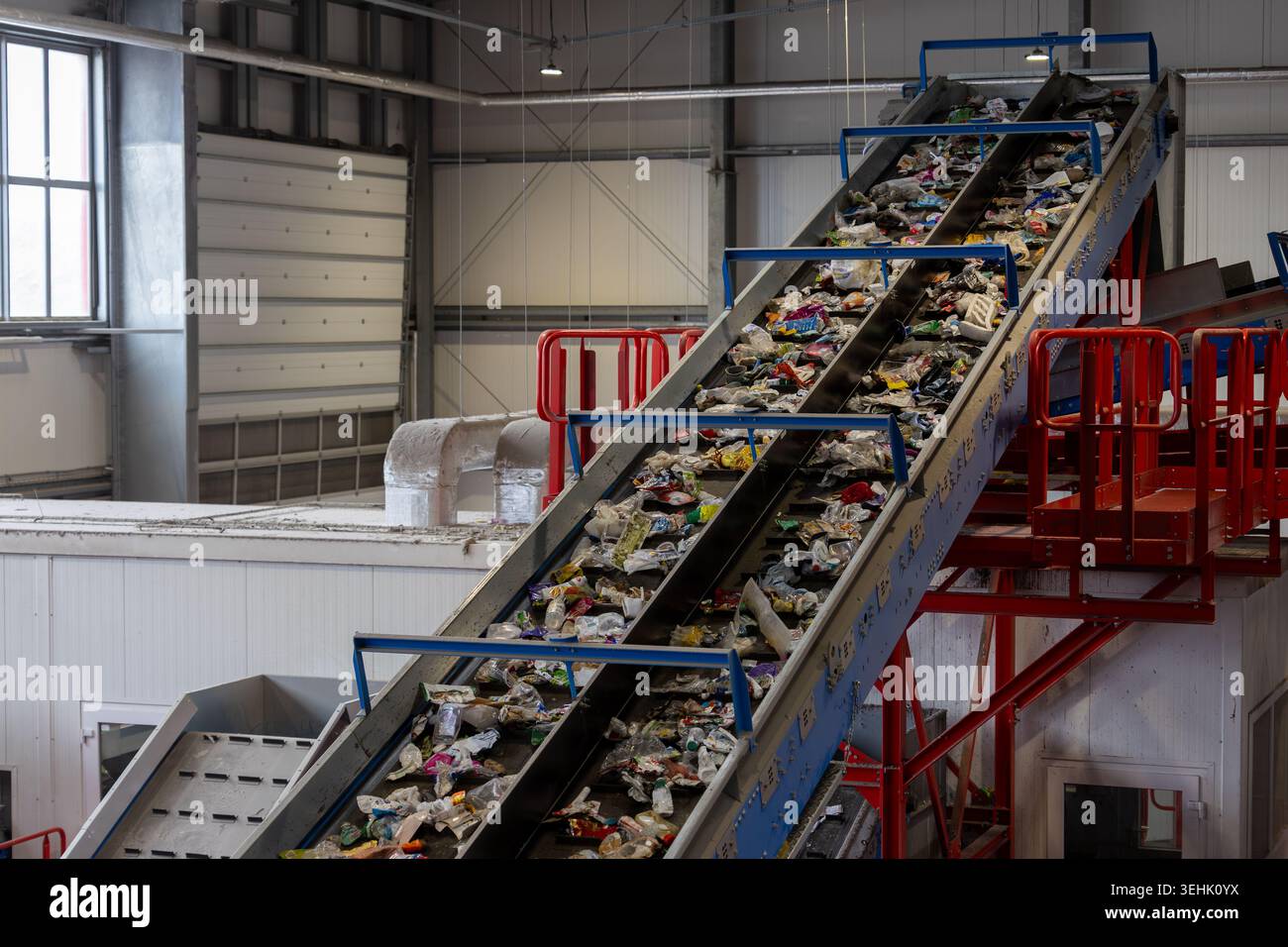 Nastro trasportatore per il trasporto di rifiuti domestici e di plastica misti all'interno di un impianto di riciclaggio. Sistema di smistamento industriale con linee di trattamento automatizzate Foto Stock