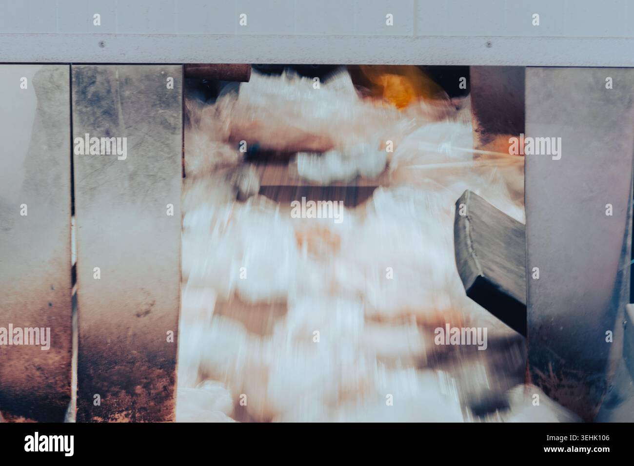 Materiali di scarto di plastica che passano attraverso apparecchiature di riciclaggio automatizzate all'interno di un impianto di trattamento. Effetto di sfocatura del movimento sul flusso di rifiuti in movimento Foto Stock