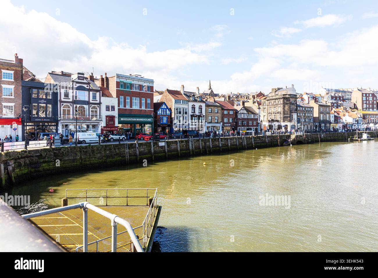 Una scena sul lungomare a Whitby, North Yorkshire, che mostra una fila di edifici storici lungo il bordo del porto. Il mix di mattoni e facciate renderizzate, fai shopping Foto Stock