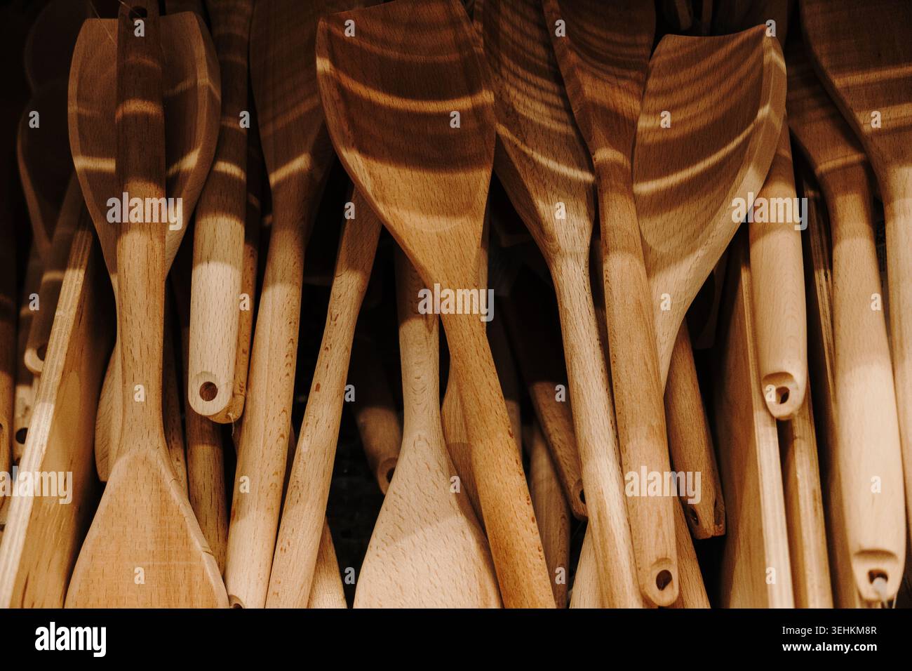 Spatole di legno assortite e utensili da cucina esposti in un negozio di articoli per la casa. Concetto di accessorio da cucina naturale con estetica di stile di vita rustico. Foto Stock