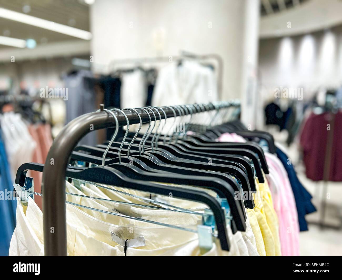 Portapacchi con abiti da donna in negozio. Appendiabiti estivi da vicino. Immagine per negozi e vendite Foto Stock