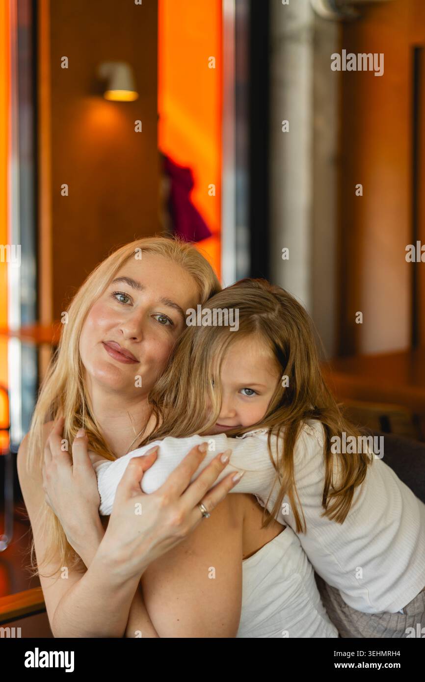 Una madre e una figlia condividono un momento tenero in un accogliente caffè. La scena cattura l'essenza della maternità, dei legami familiari e delle semplici gioie del bambino Foto Stock