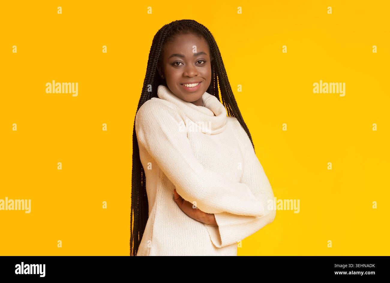 Sfondo giallo brillante con una donna sorridente in un comodo pullover Foto Stock