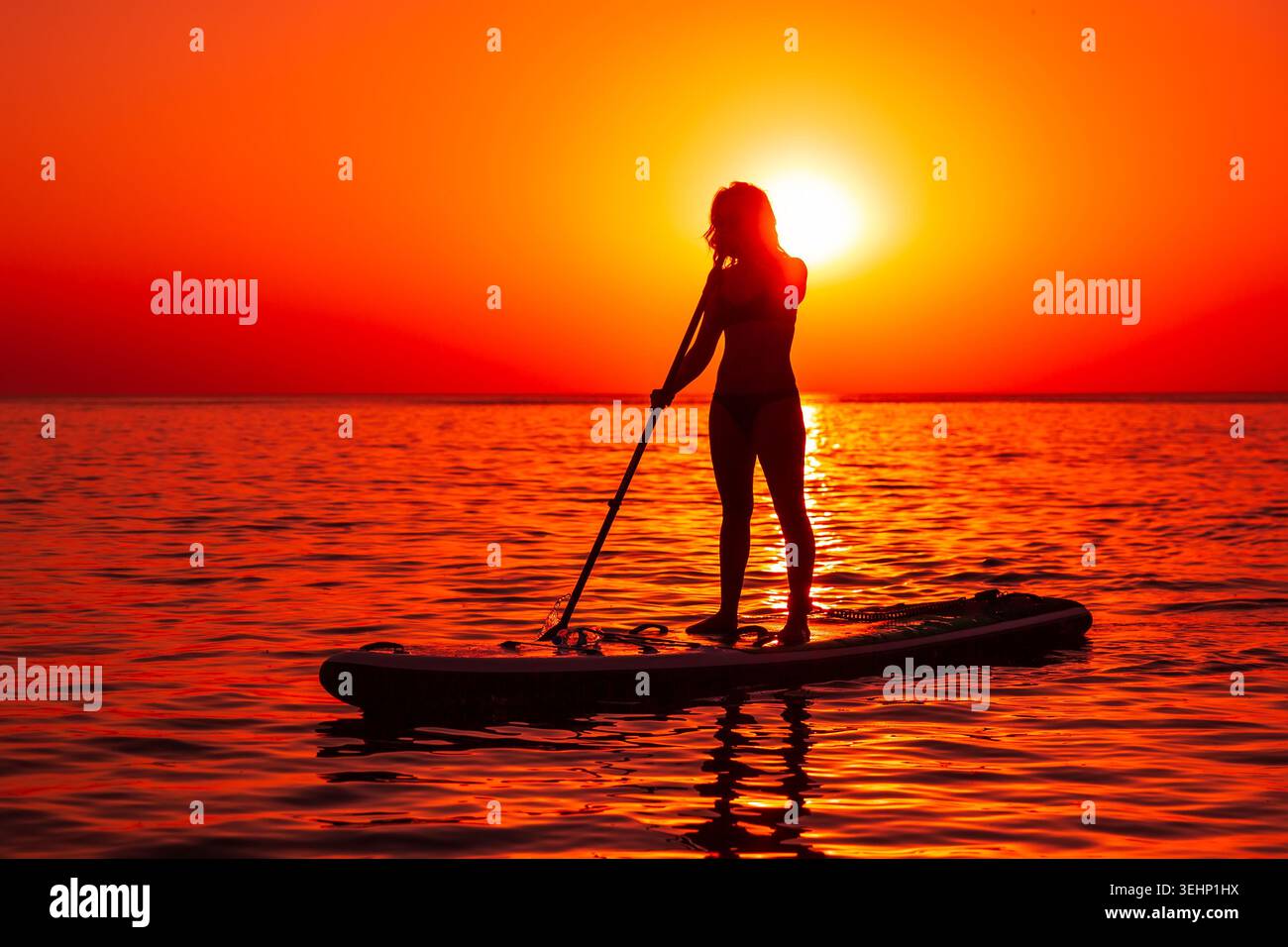 24 maggio 2026. Antalya, Turchia. Silhouette di donna pagaiata sul mare calmo durante il vivace tramonto arancione Foto Stock