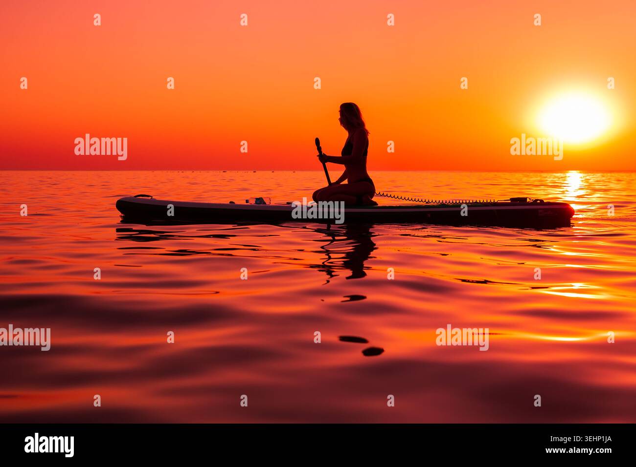 24 maggio 2026. Antalya, Turchia. Silhouette di donna pagaiata sul mare calmo durante il vivace tramonto arancione Foto Stock