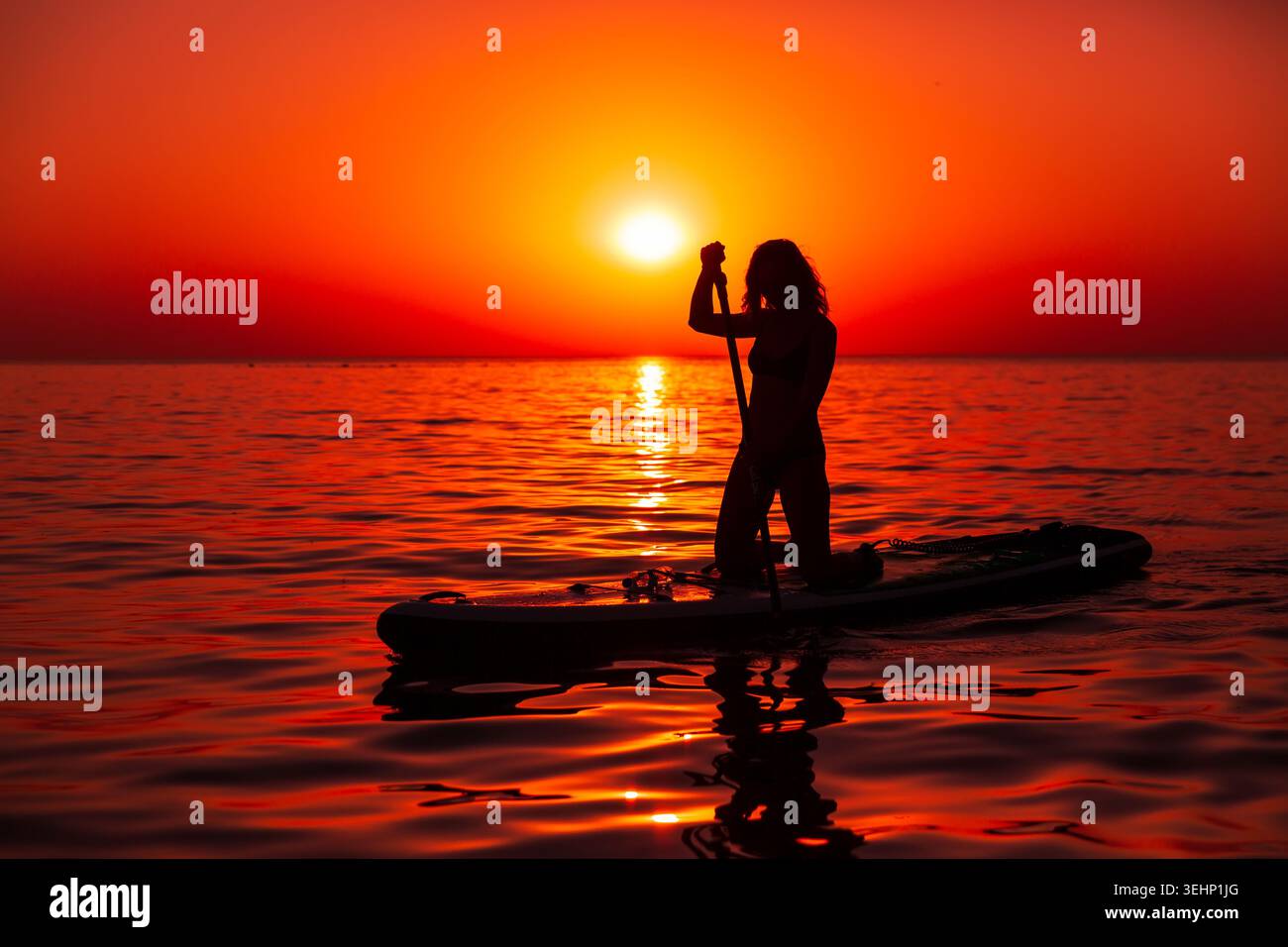 24 maggio 2026. Antalya, Turchia. Silhouette di donna pagaiata sul mare calmo durante il vivace tramonto arancione Foto Stock