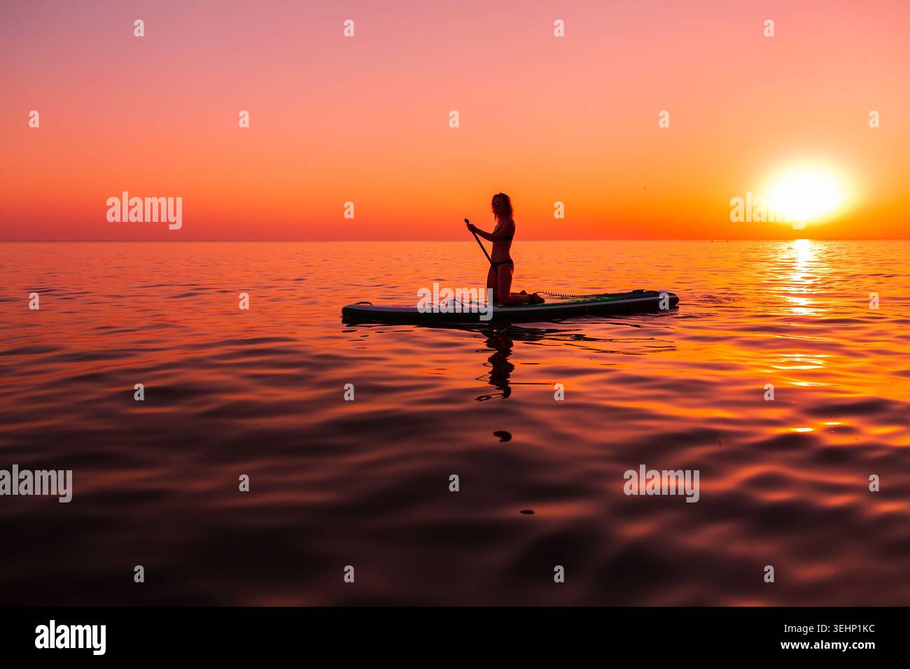 24 maggio 2026. Antalya, Turchia. Silhouette di donna pagaiata sul mare calmo durante il vivace tramonto arancione Foto Stock