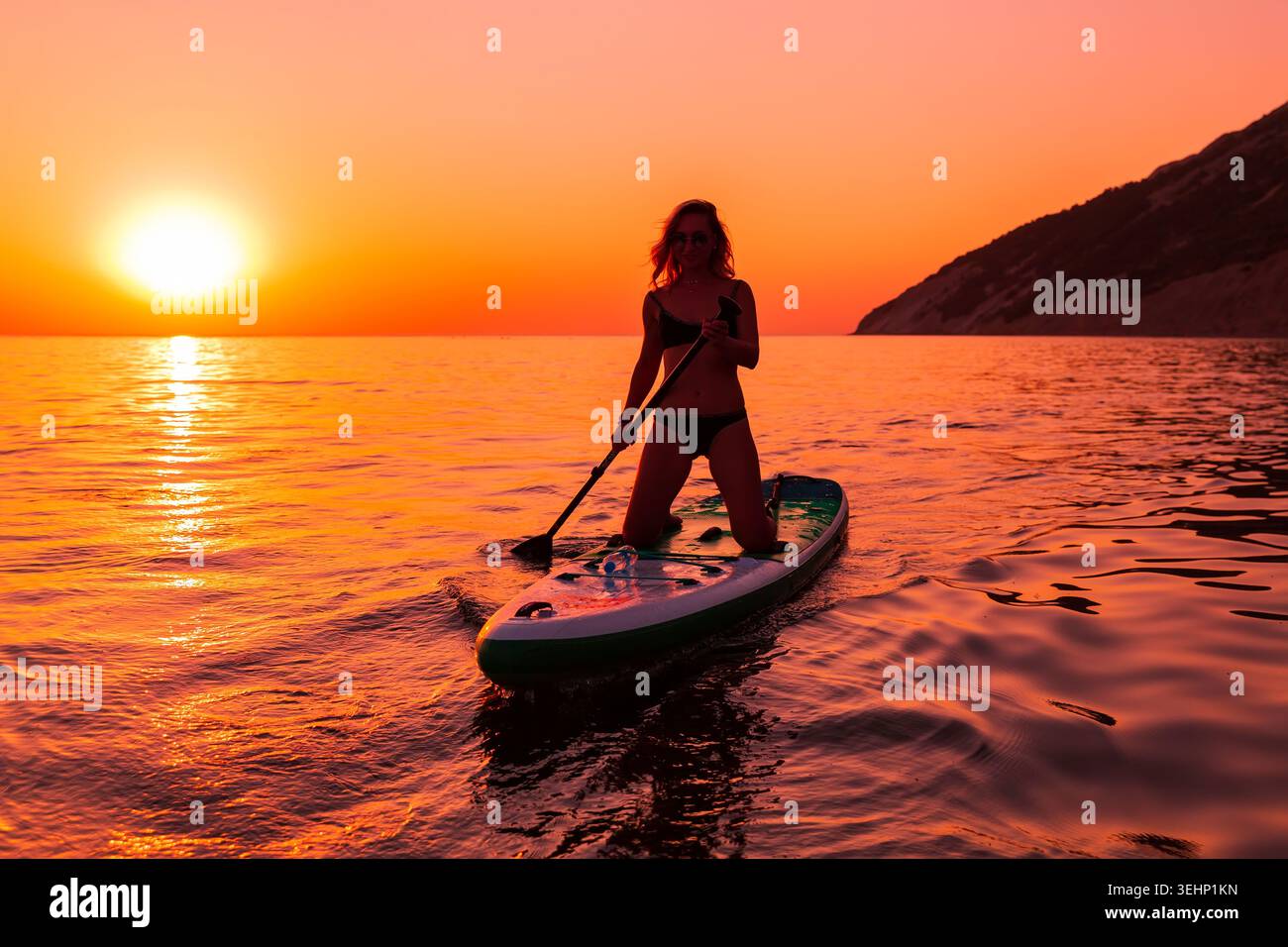 24 maggio 2026. Antalya, Turchia. Silhouette di donna pagaiata sul mare calmo durante il vivace tramonto arancione Foto Stock