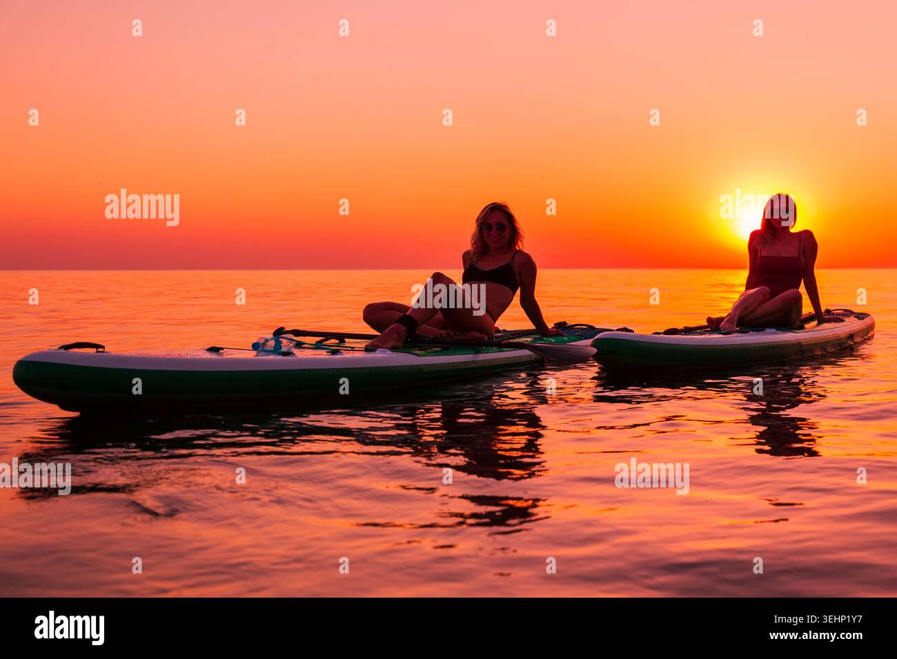 24 maggio 2026. Antalya, Turchia. Due donne che si rilassano sulle tavole da paddle al tramonto sul calmo mare tropicale Foto Stock