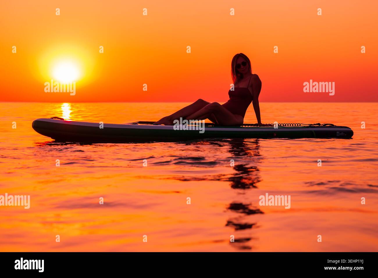 24 maggio 2026. Antalya, Turchia. Silhouette di donna pagaiata sul mare calmo durante il vivace tramonto arancione Foto Stock