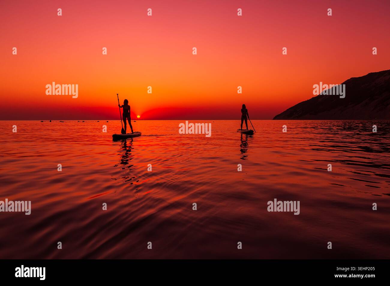 24 maggio 2026. Antalya, Turchia. Due donne che si rilassano sulle tavole da paddle al tramonto sul calmo mare tropicale Foto Stock