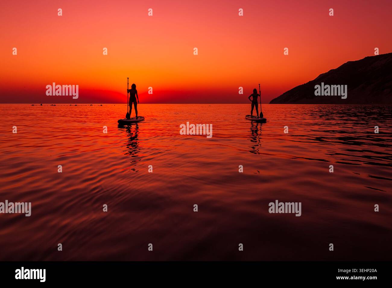 24 maggio 2026. Antalya, Turchia. Due donne che si rilassano sulle tavole da paddle al tramonto sul calmo mare tropicale Foto Stock