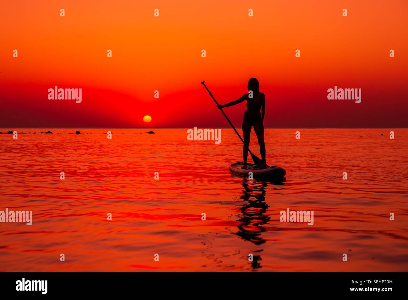 24 maggio 2026. Antalya, Turchia. Silhouette di donna pagaiata sul mare calmo durante il vivace tramonto arancione Foto Stock
