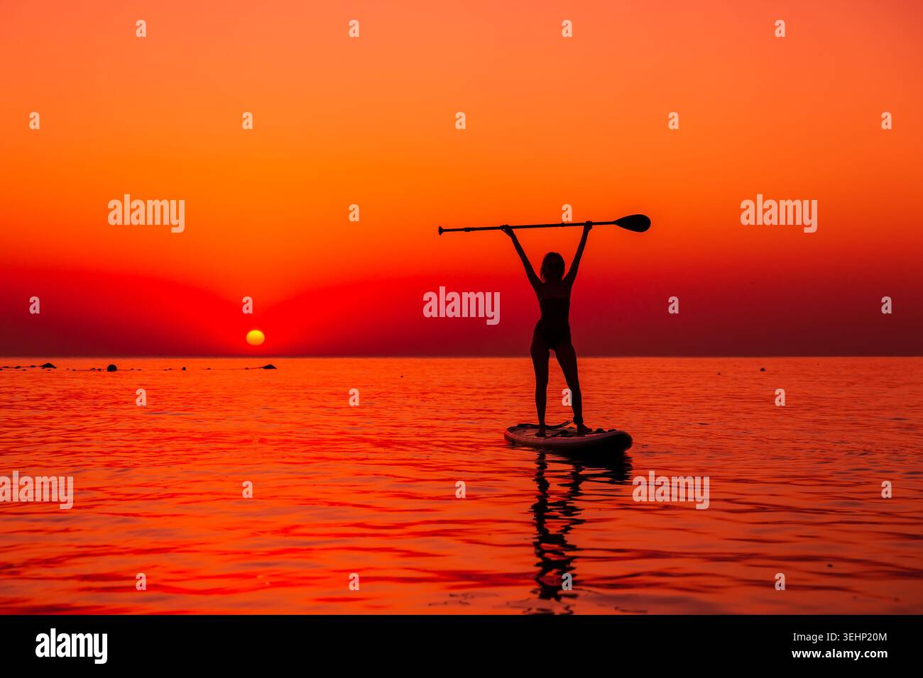 24 maggio 2026. Antalya, Turchia. Silhouette di donna pagaiata sul mare calmo durante il vivace tramonto arancione Foto Stock