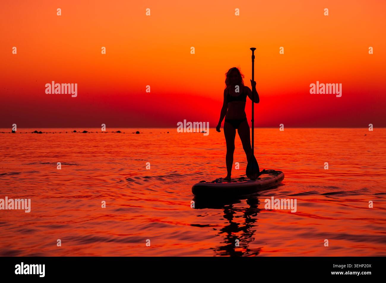 24 maggio 2026. Antalya, Turchia. Silhouette di donna pagaiata sul mare calmo durante il vivace tramonto arancione Foto Stock