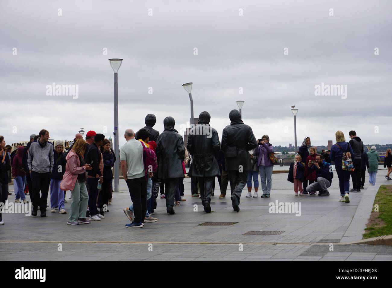 Turisti e visitatori si riuniscono intorno alla famosa statua dei Beatles in bronzo sul lungomare di Pier Head. Foto Stock