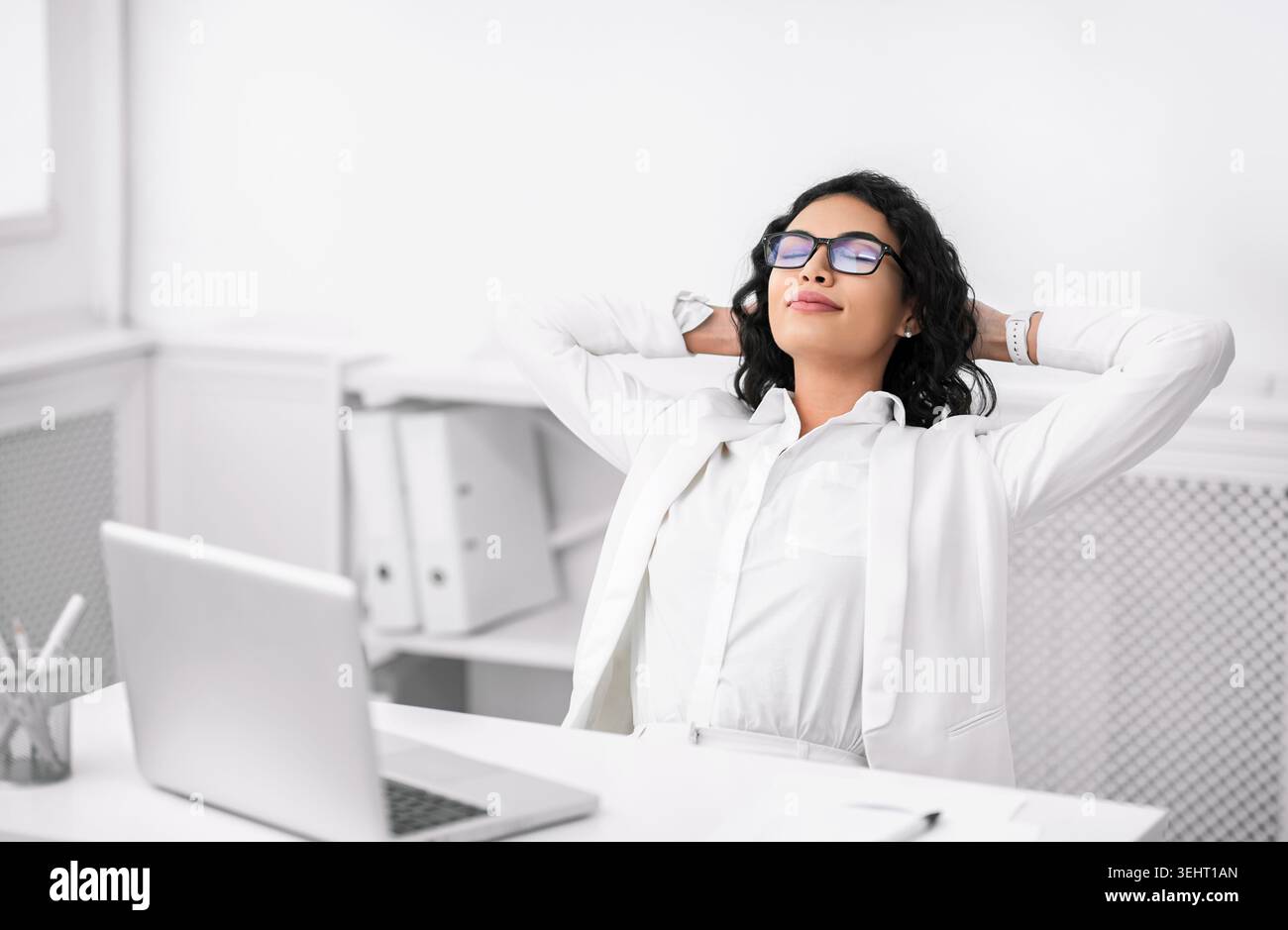 Donna d'affari ispanica in occhiali che si rilassa al lavoro Foto Stock