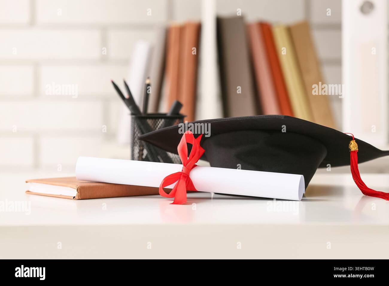 Diploma con libro e mortaio sul tavolo bianco Foto Stock
