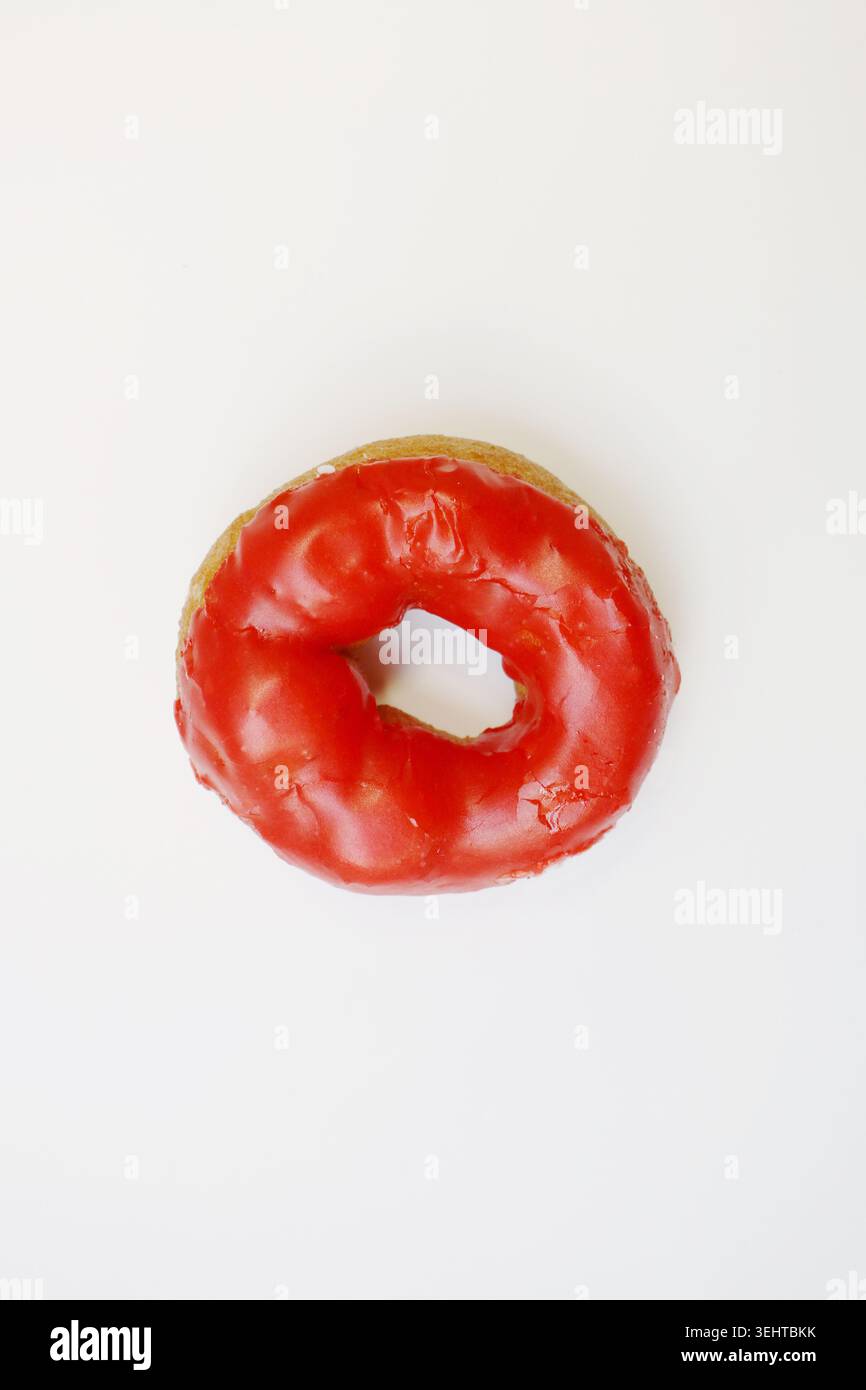 Glassa rossa brillante con finitura liscia. La composizione semplice evidenzia il dolce fascino del dessert. Ideale per blog di cibo e menu Foto Stock