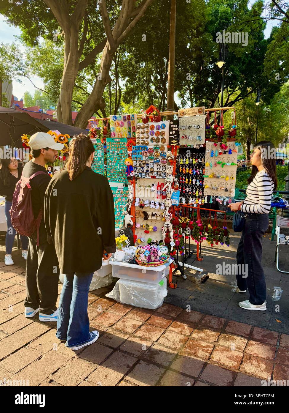 Gli amanti dello shopping curiosano in una colorata banchina di mercato che vende gioielli e accessori fatti a mano a Coyoacán, città del Messico, Messico Foto Stock
