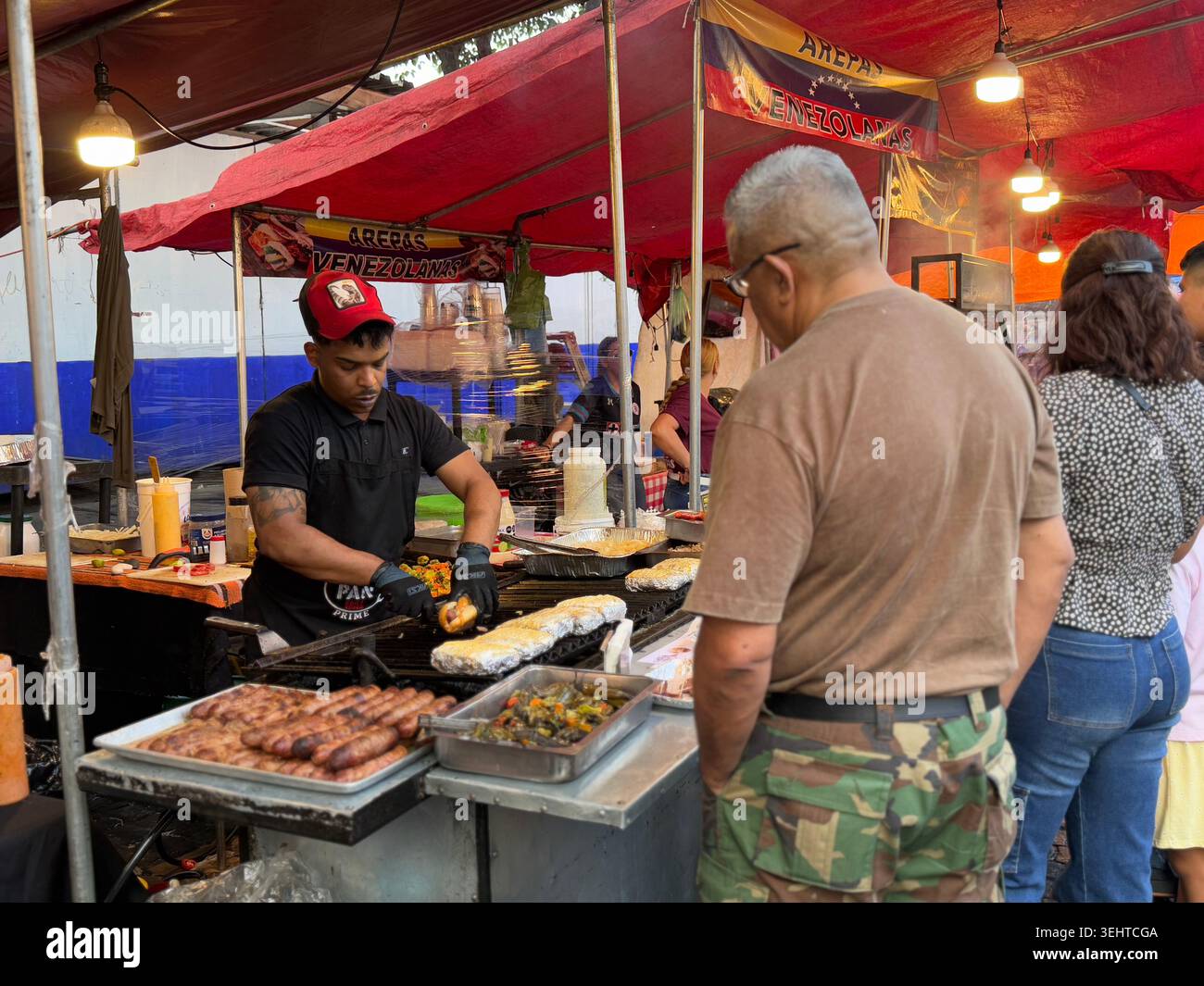 Un venditore prepara arepas venezuelane in un affollato stand di Street food a Coyoacán, città del Messico, Messico - Immagine stock catturata con smartphone