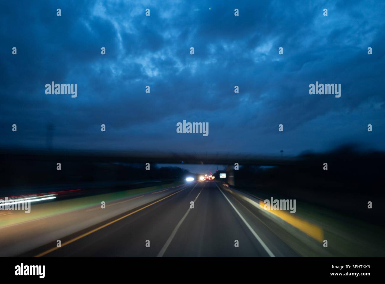 Asfalto traffico notturno dell'autostrada con sfocatura del movimento dei fari delle auto lungo il percorso Foto Stock