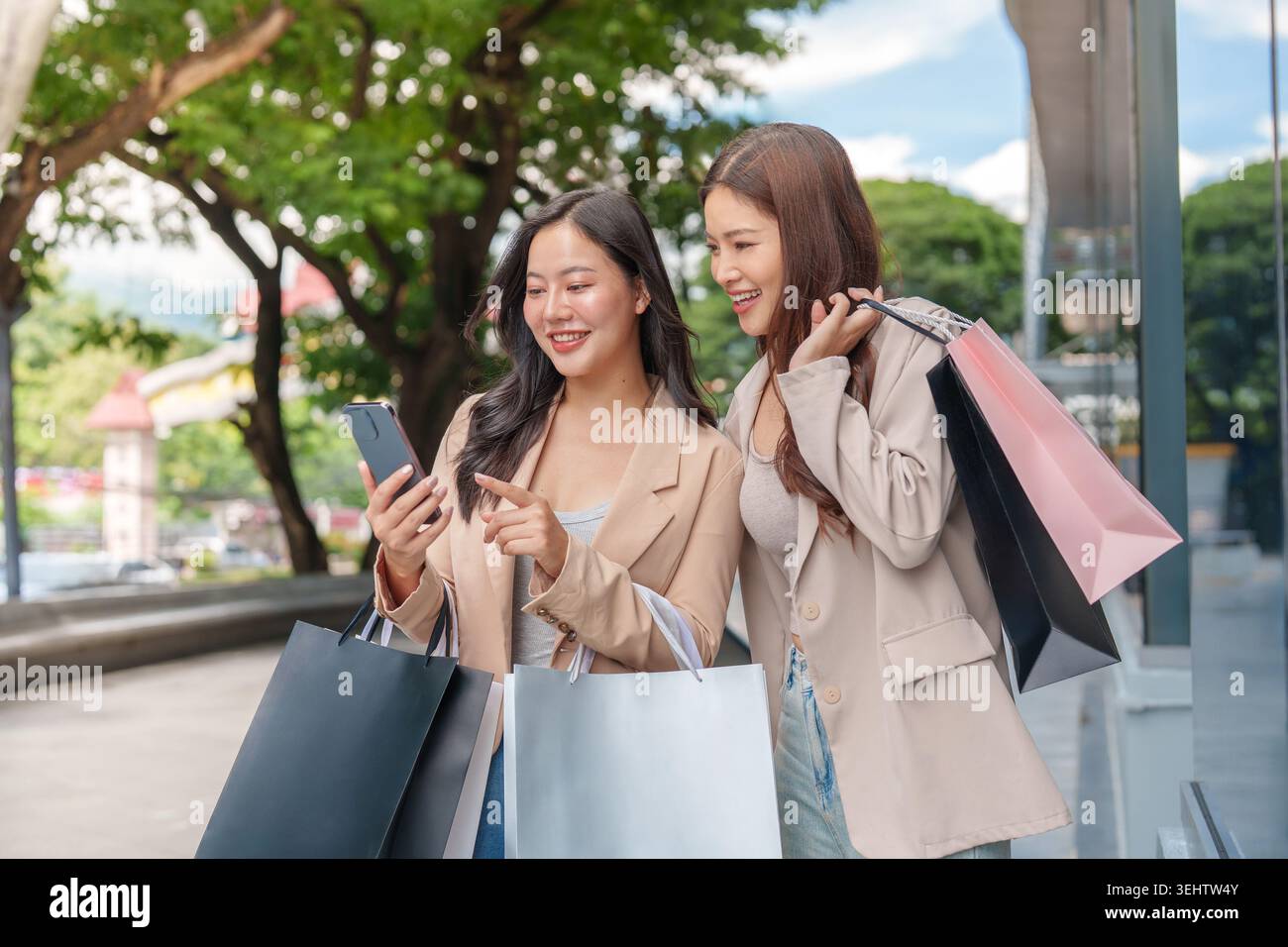 Felici donne asiatiche amici che fanno shopping e guardano smartphone Foto Stock