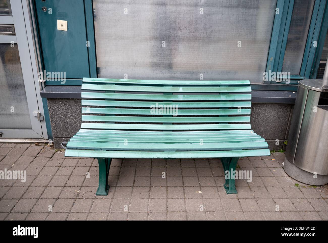 Panca vuota di legno verde vicino alla facciata dell'edificio urbano in un ambiente urbano minimalista Foto Stock