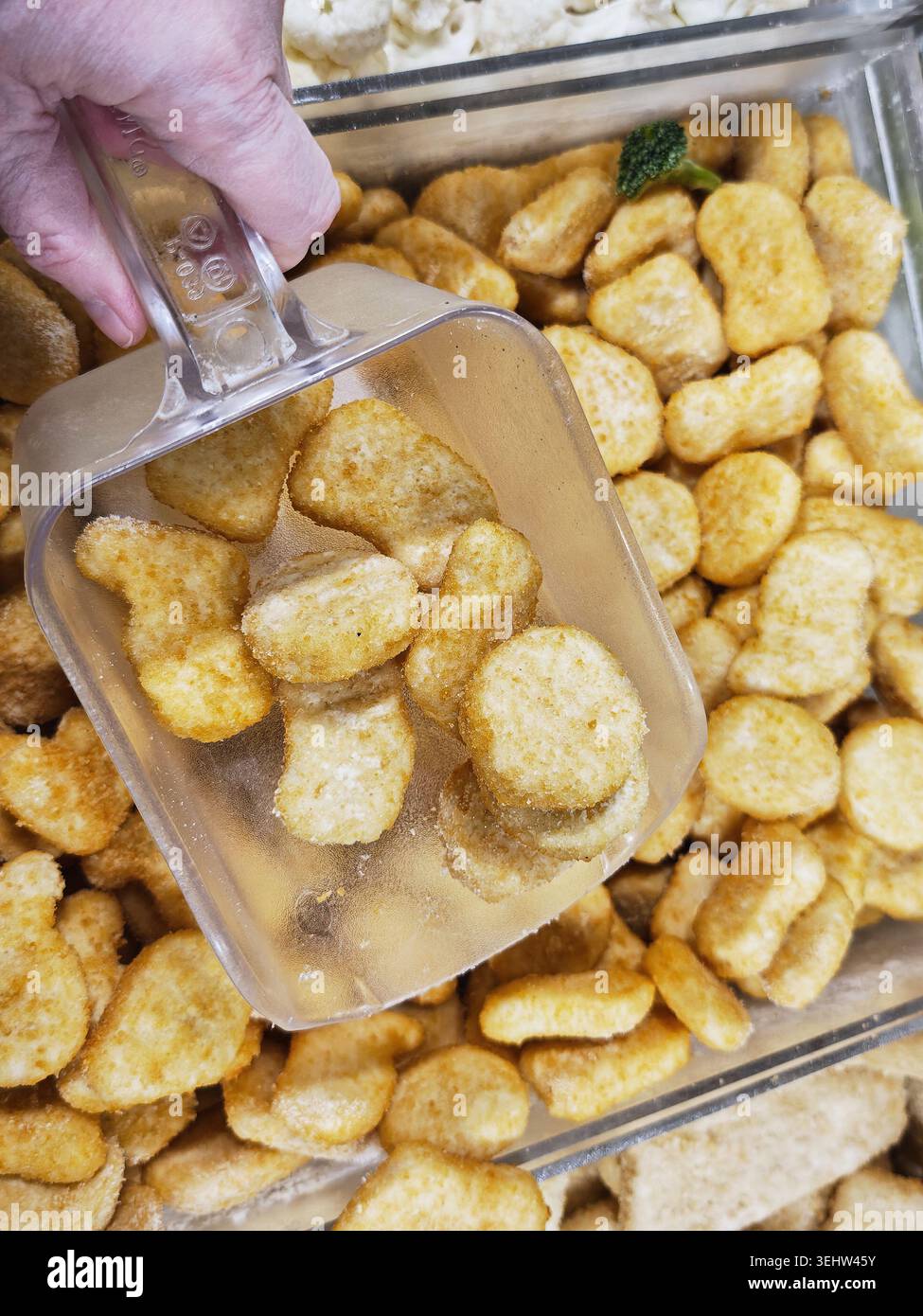 I clienti acquistano snack in un negozio di alimentari. Scelgono articoli da un'esposizione di alimenti in grandi quantità in contenitori trasparenti. Foto Stock