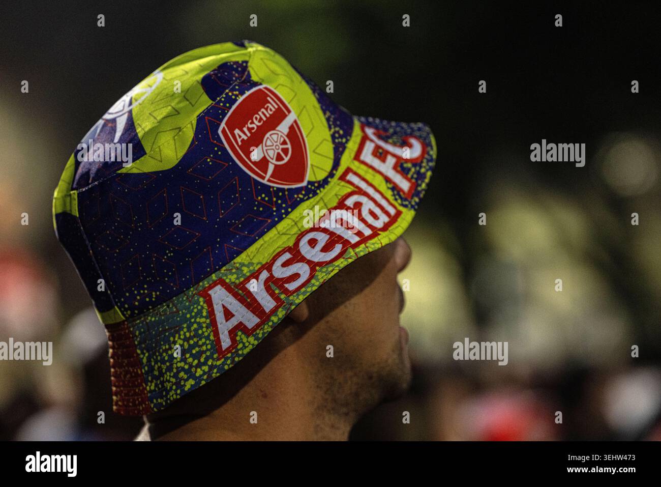 Foto ravvicinata di un tifoso di calcio che indossa un cappello giallo, blu e rosso brillante dell'Arsenal F.C. Foto Stock