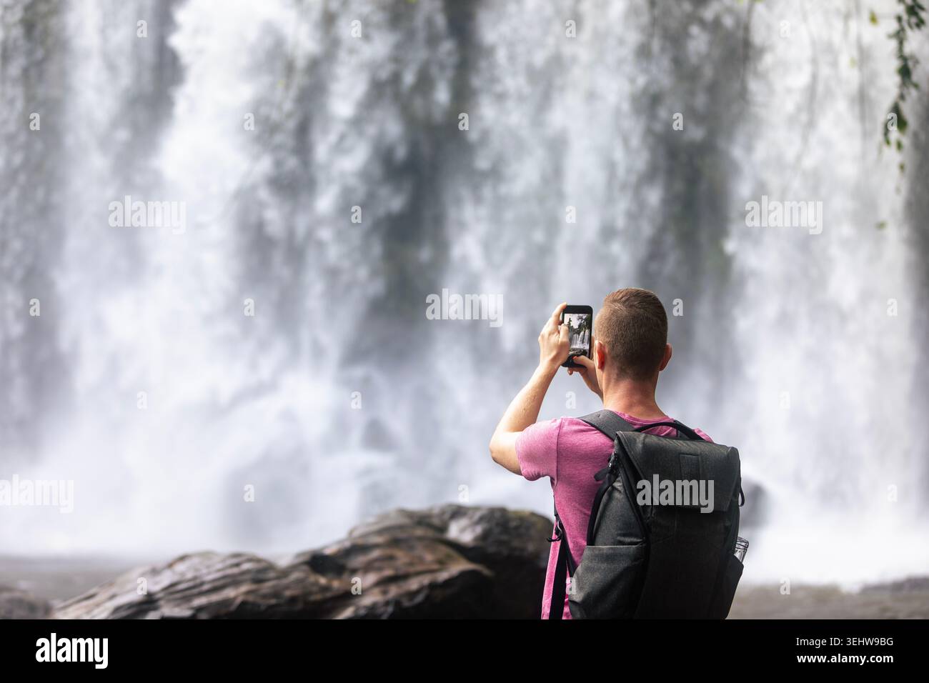 Le riprese turistiche della cascata di Phnom Kulen con telefono cellulare nella giungla della Cambogia. Video su smartphone, blog di viaggio, tecnologia e vacanza tropicale Foto Stock