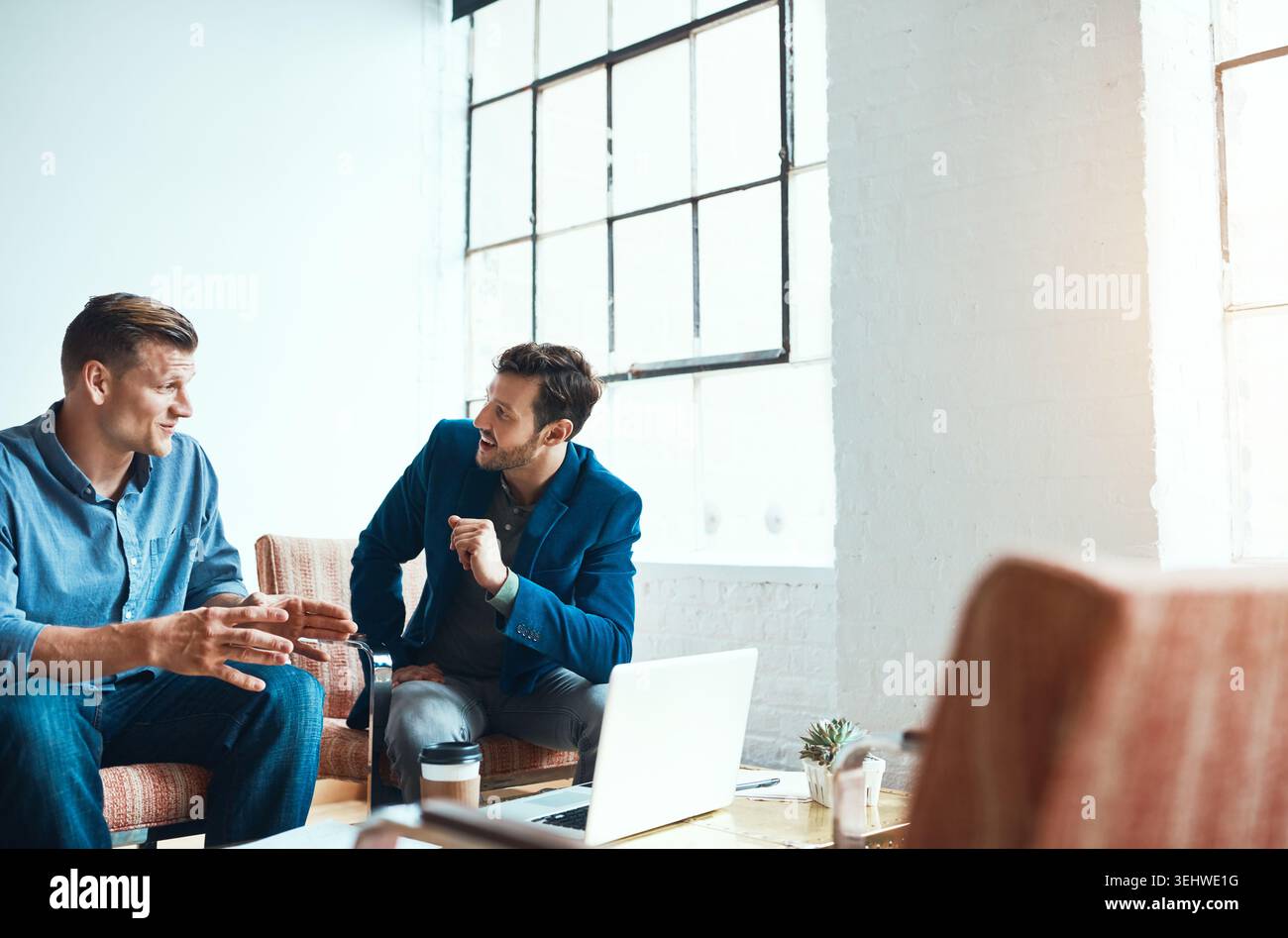 Uomini, parlate e fate ricerche in ufficio con notebook, collaborazione e tendenze online per il marketing digitale. Persone, conversazioni e idee sul posto di lavoro con Foto Stock
