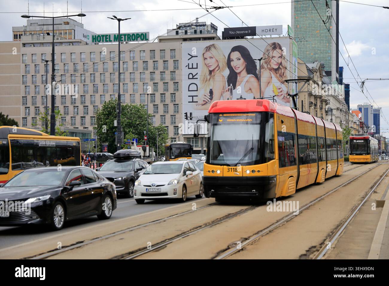 Tram linea n.7 in corsa sulla corsia riservata di via Marszalkowska (Ulica Marszalkowska) con un enorme cartellone pubblicitario su un edificio alle spalle e altri veicoli che circolano sulla strada accanto nel centro città. Varsavia. Polonia Foto Stock