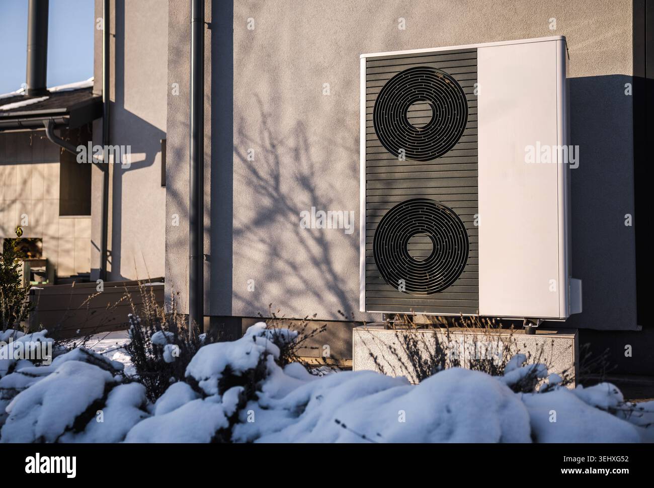 Moderna pompa di calore a sorgente d'aria installata all'esterno di un edificio residenziale in inverno. Foto Stock