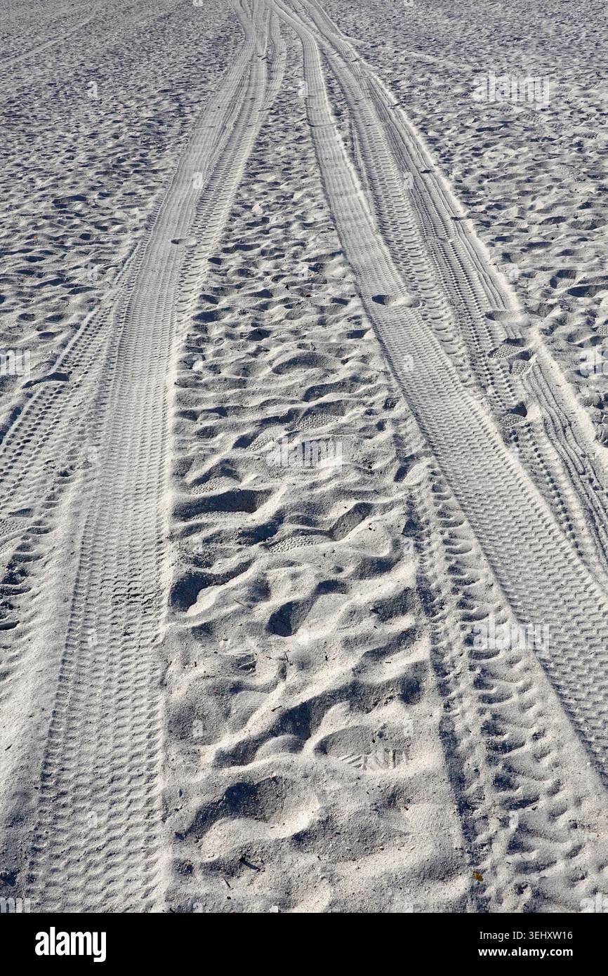 Tracce di pneumatici e numerose impronte in sabbia di colore chiaro, creando una superficie ruvida. Le due tracce degli pneumatici sono parallele, indicando il passaggio del veicolo. Foto Stock