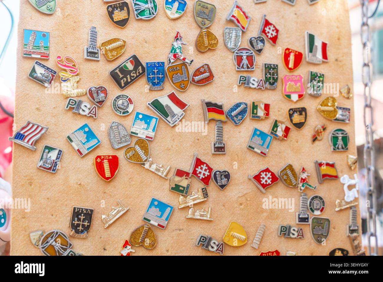 Pisa, Italia, 07.05.25, distintivi di viaggio colorati provenienti da luoghi diversi disposti su sfondo di sughero. Simbolo di viaggi, cultura e souvenir. Foto Stock