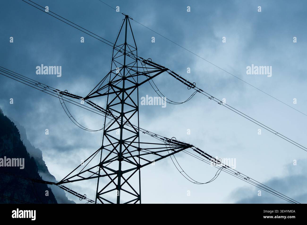 Vista simmetrica ad angolo basso di un pilone elettrico ad alta tensione o di una torre Powerline. Struttura geometrica in acciaio contro il cielo azzurro, con Foto Stock