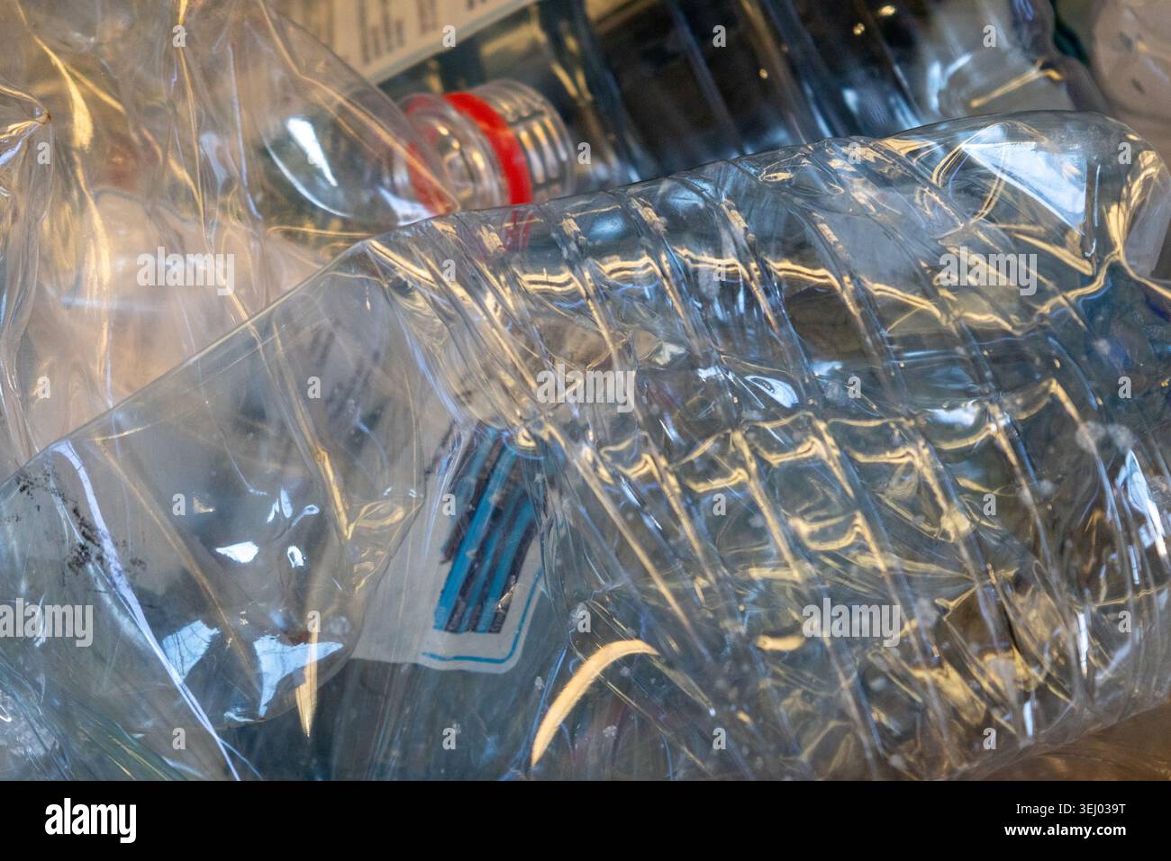 Le bottiglie di plastica sono impilate in un contenitore di riciclaggio che mostra l'importanza del riciclaggio e della gestione dei rifiuti nella comunità durante il pomeriggio. Foto Stock