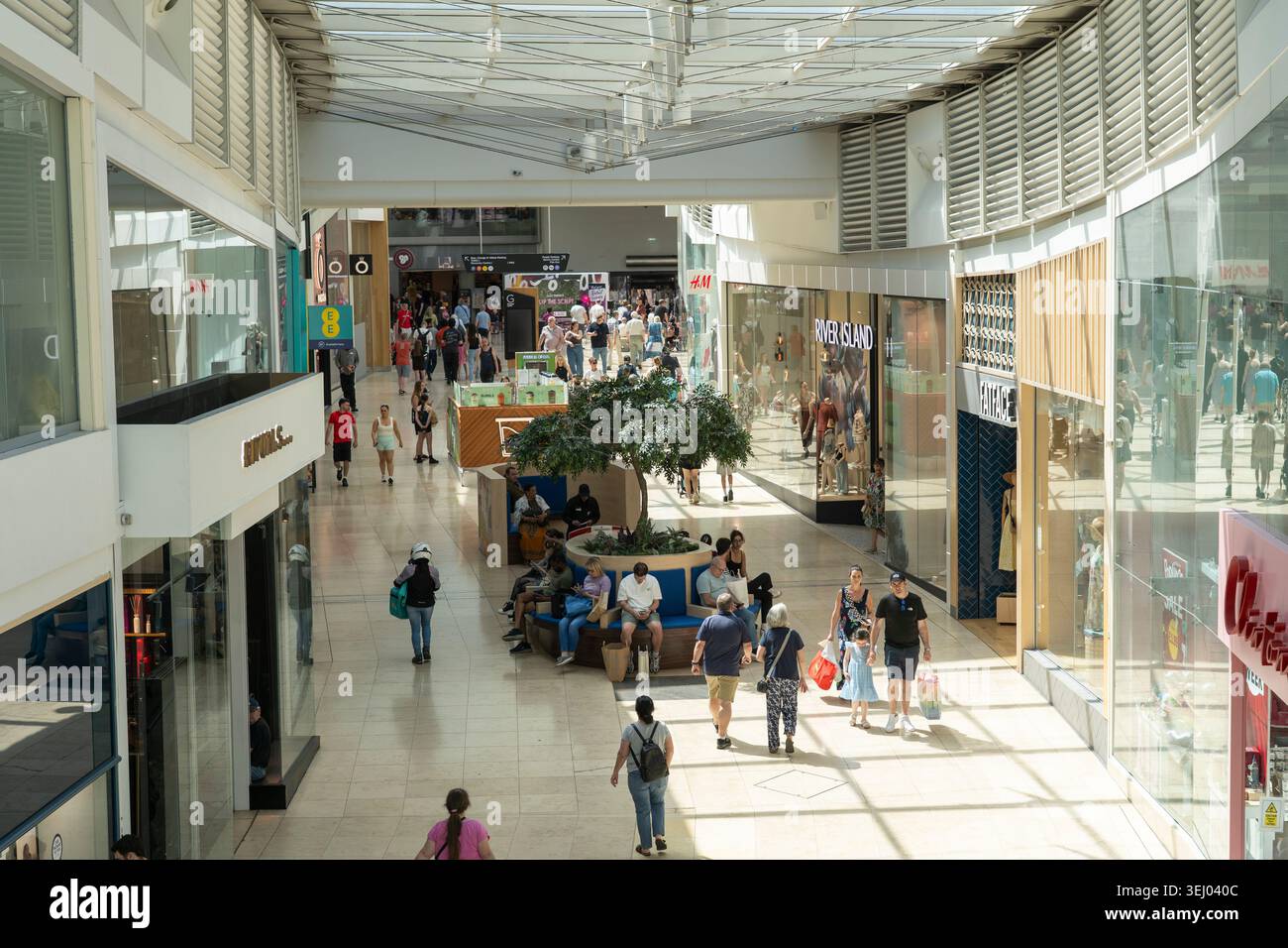 Persone che fanno shopping nel Festival Place, camminano attraverso un grande atrio coperto di vetro che lascia entrare la luce del sole, Basingstoke, Regno Unito. Concetto: Costo della vita Foto Stock