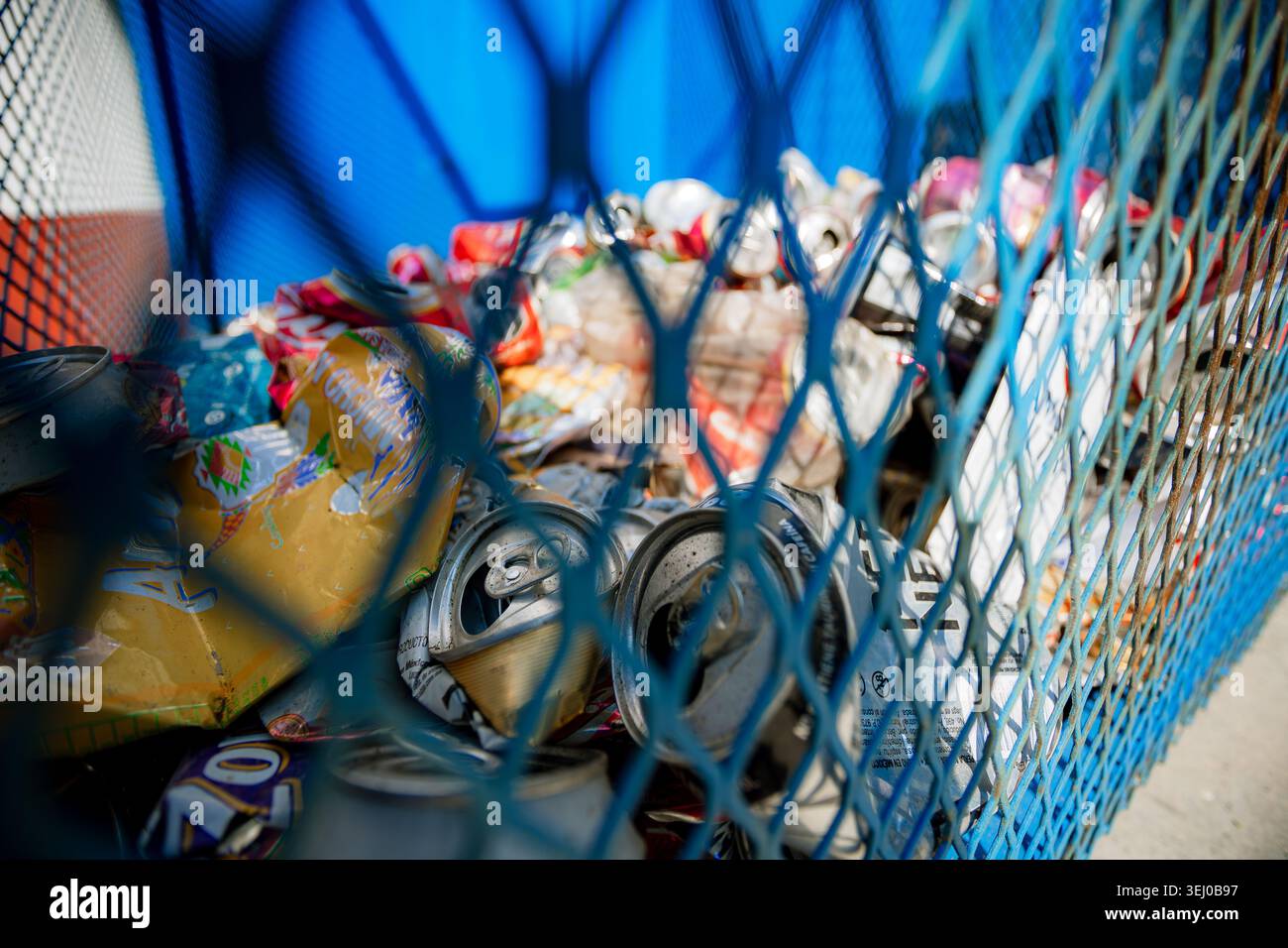 Uno scatto ravvicinato attraverso una rete metallica mostra le lattine di bibite frantumate raccolte per il processo di riciclaggio ambientale. Foto Stock