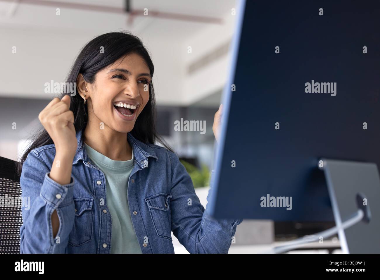 Una donna indiana felice celebra il successo professionale sul posto di lavoro Foto Stock