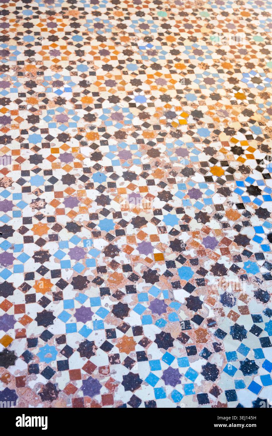 Il mosaico zellige copre il pavimento della Madrasa Ben Youssef a Marrakech, Marocco. I coloratissimi motivi geometrici mostrano un design artistico tradizionale. I visitatori ammirano i dettagli intricati. Foto Stock