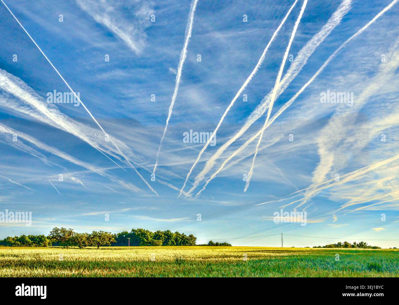 Le prime tracce di vapore del mattino / si contrappongono in alto sopra la Francia centrale da aerei jet che friggono verso sud da Parigi. Foto Stock