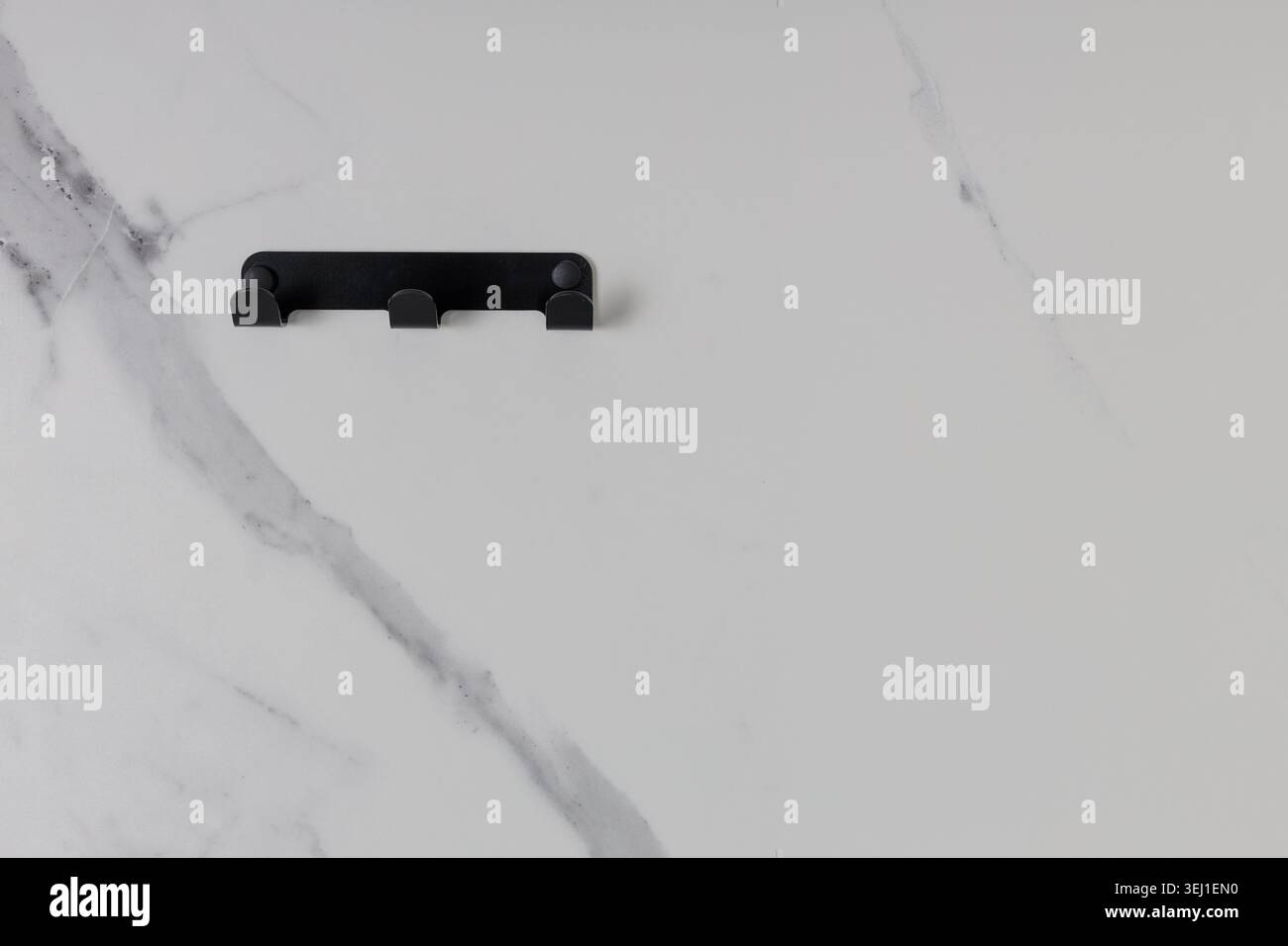 Gancio da parete in metallo nero su sfondo in marmo Foto Stock