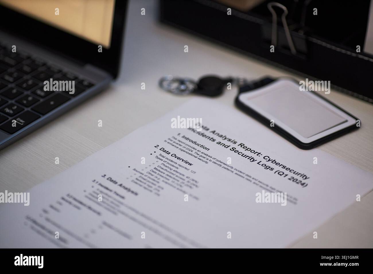 Primo piano del rapporto sulla sicurezza informatica accanto a laptop, portachiavi, supporto badge, visualizzazione del flusso di lavoro di revisione dei dati e monitoraggio della sicurezza. Utile per la gestione dei rischi IT, la conformità e i contenuti di controllo Foto Stock