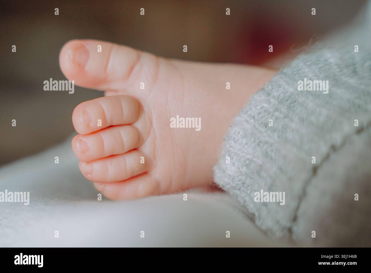 Il piede di un neonato su uno sfondo di colore chiaro le dita sono rilassate, la pelle è liscia e morbida con una consistenza visibile. Foto di alta qualità Foto Stock